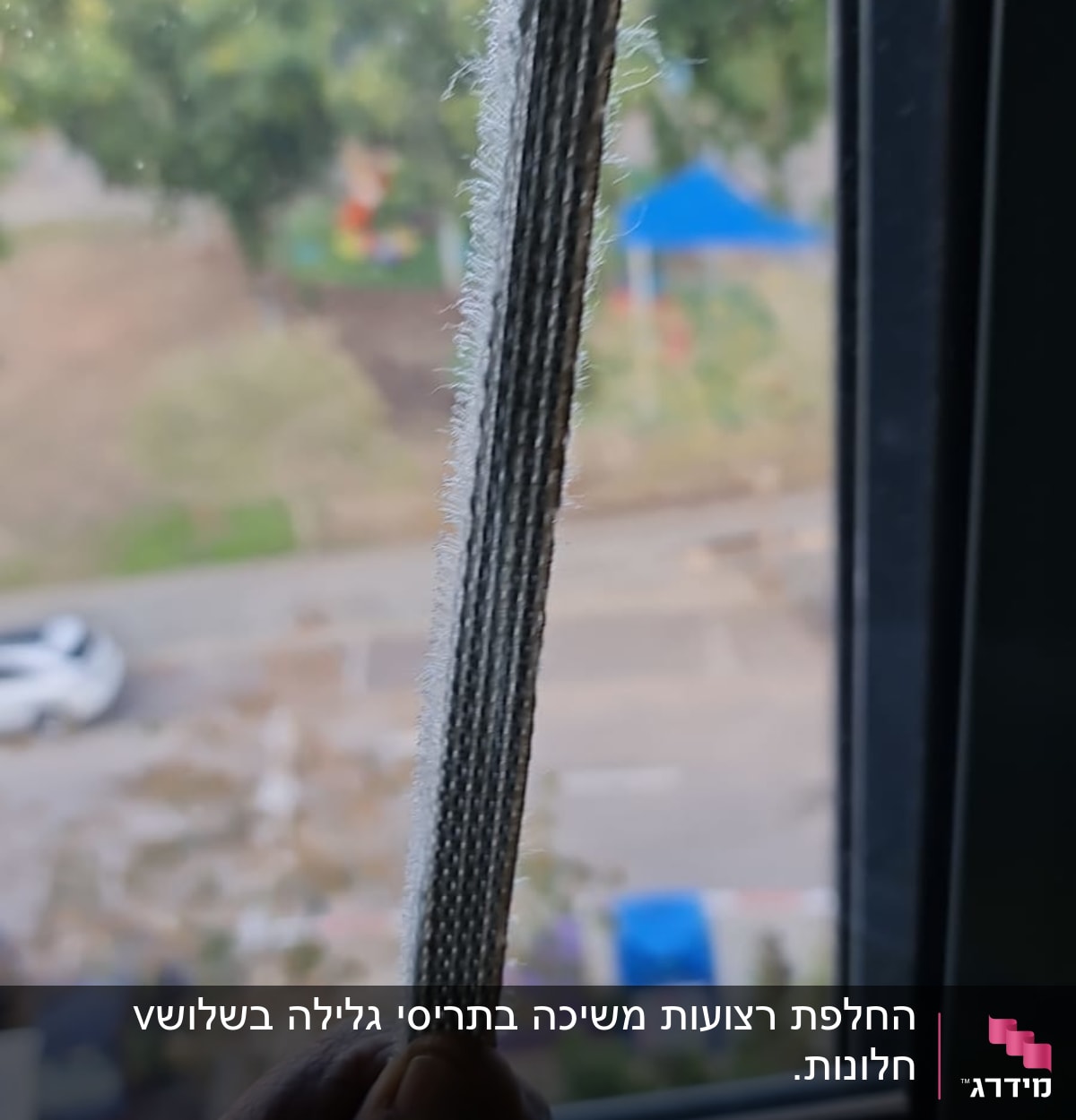 יד מחזיקה חבל תריס ליד חלון